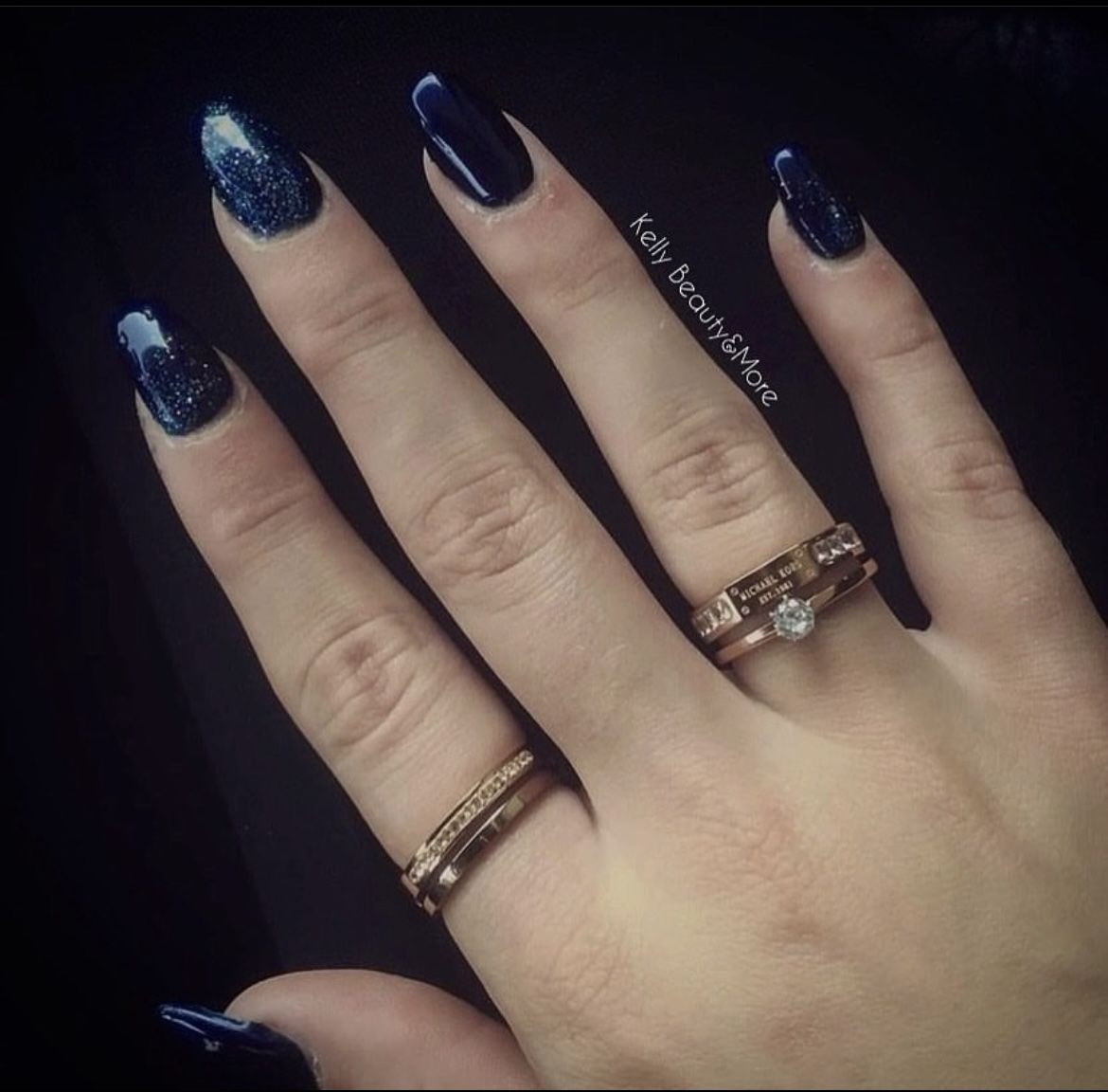 Hand met donkerblauwe glitternagels en ringen